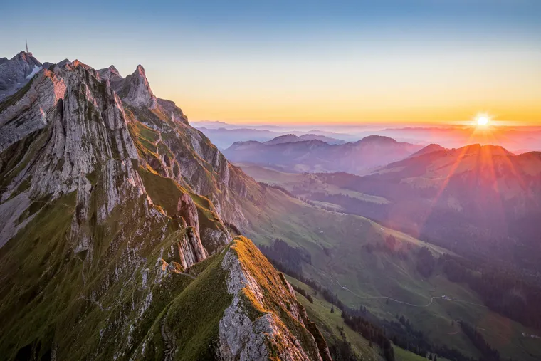 Felsgrat im Alpstein bei Sonnenuntergang, dahinter Hügelketten im Dunst