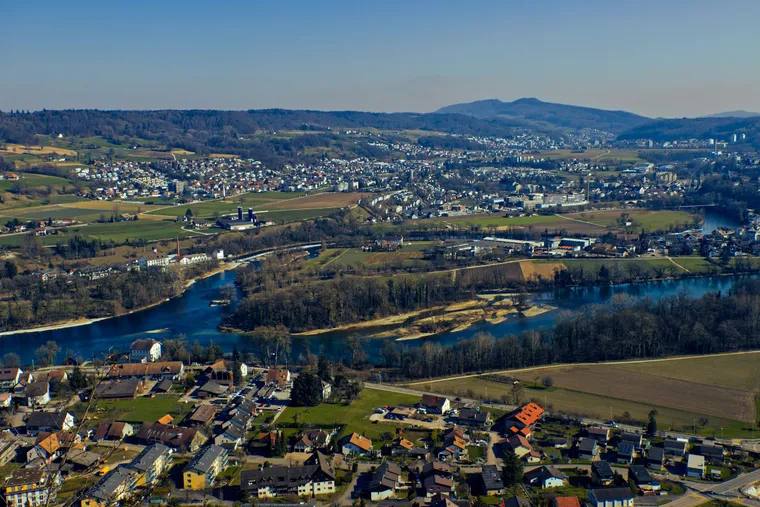 Die Aare in Schleifen durch Auenwald bei Brugg, dazu Siedlung und Felder, von oben gesehen