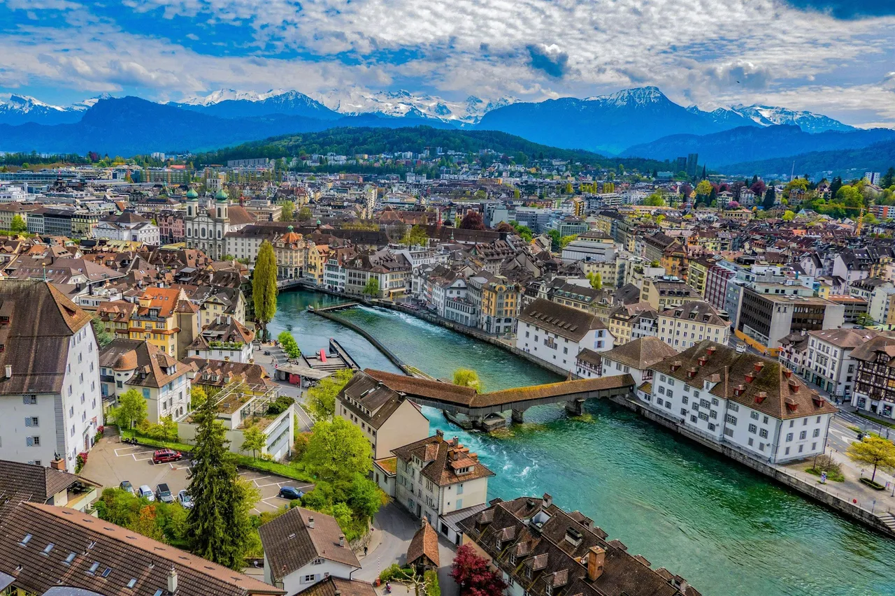 Luzern von oben mit Altstadt, Reuss und gedeckter Holzbrücke, im Hintergrund die Alpen
